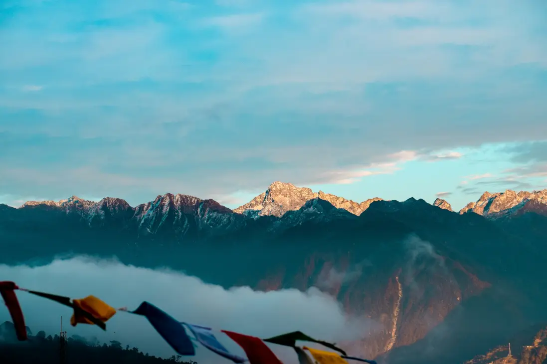 Prayer flags with snow-capped Himalayan peaks at sunrise in Arunachal Pradesh