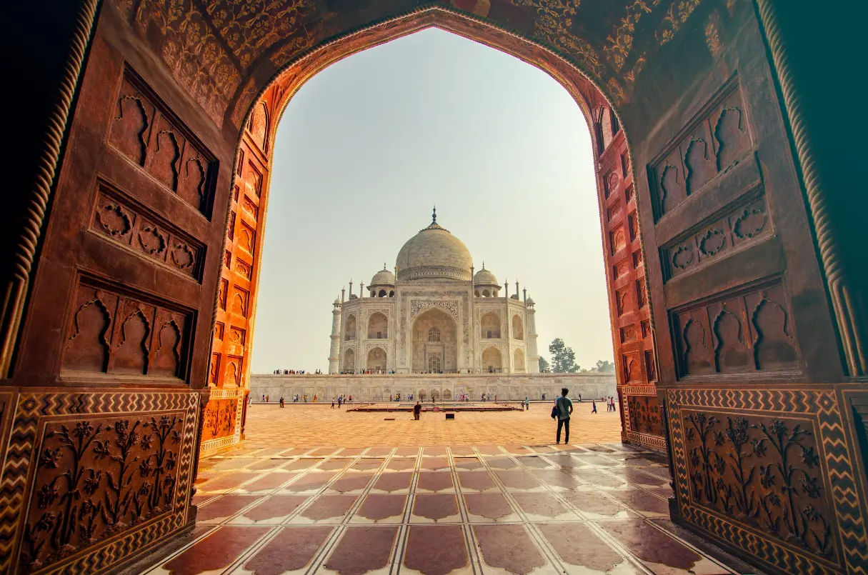 Framed view of the Taj Mahal through a grand Mughal gateway