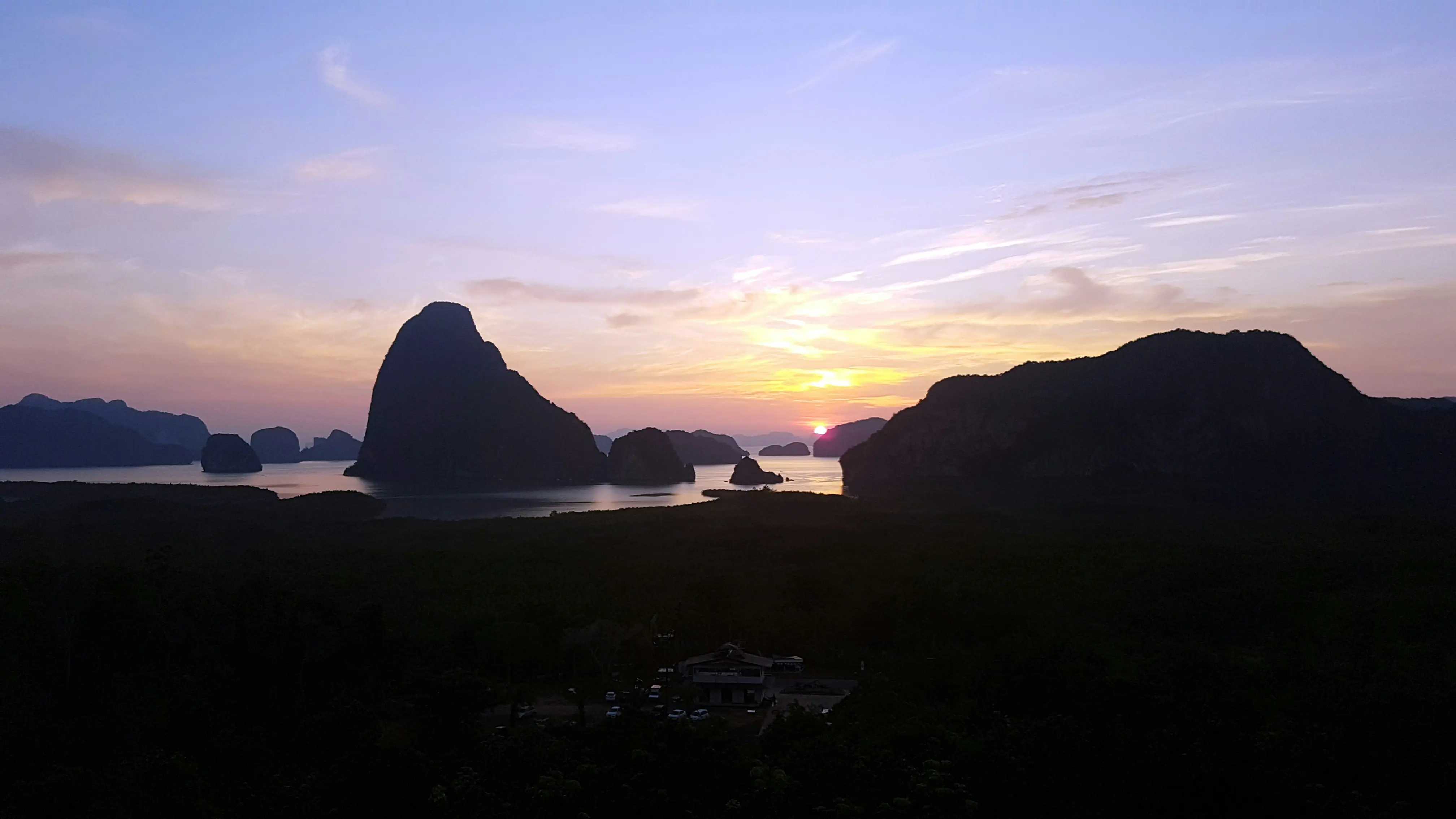 Sunset over Phang Nga Bay with silhouetted karst formations and calm waters