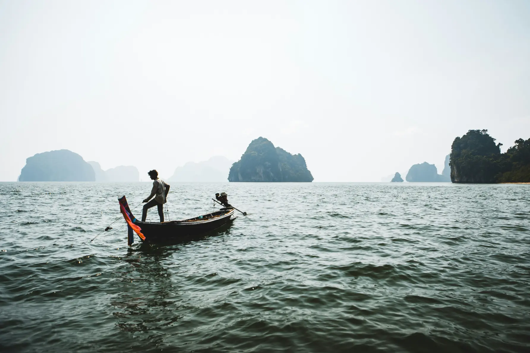 Traditional boat navigating open waters surrounded by limestone islands
