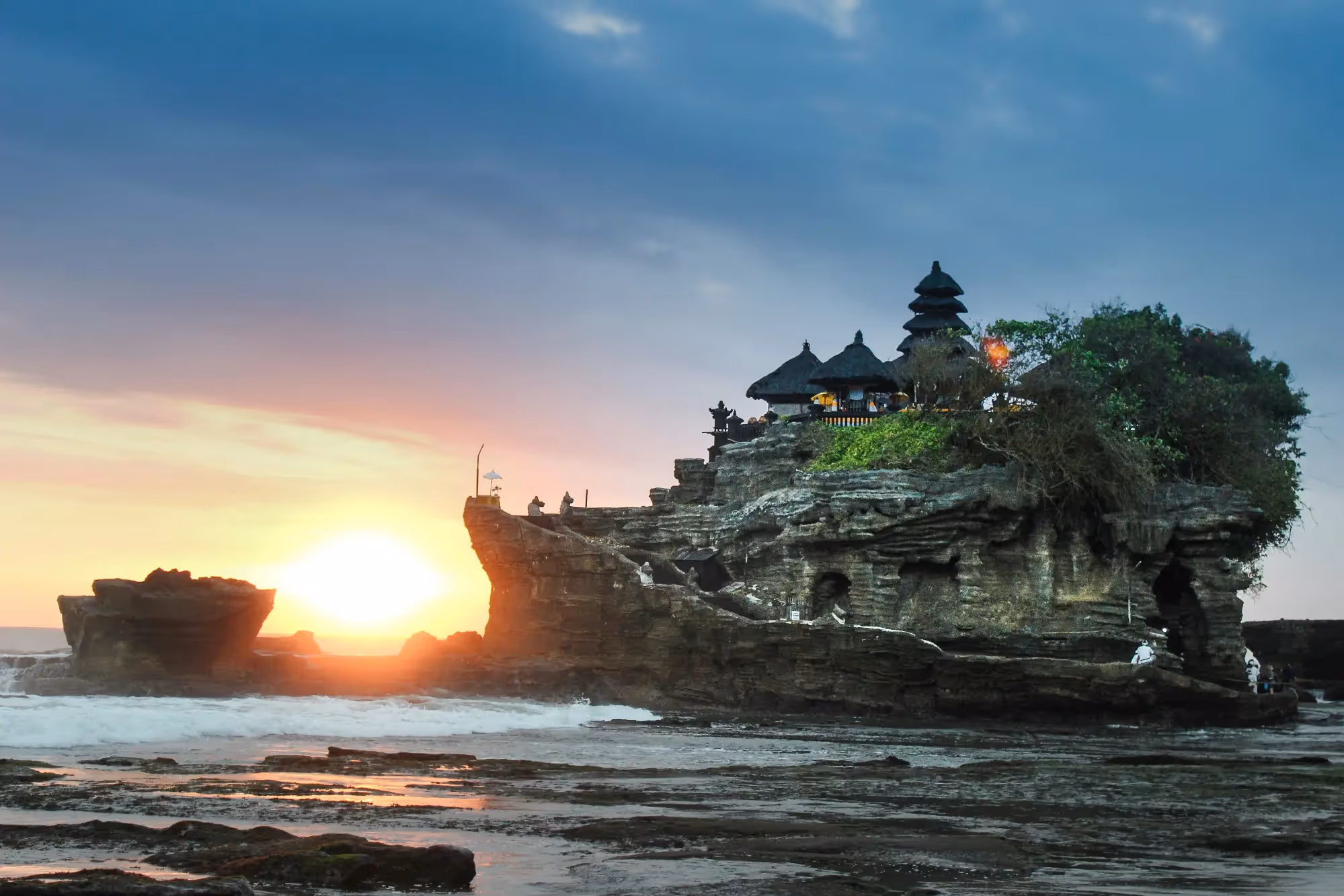 Tanah Lot sea temple in Bali at low tide, perched on a rocky outcrop with crashing waves