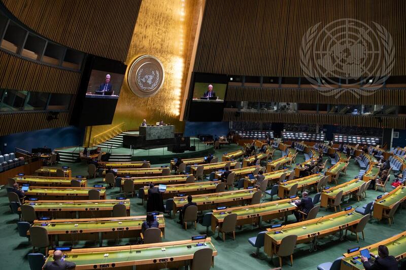 Volkan Bozkir (left at dais and on screens), President of the seventy-fifth session of the United Nations General Assembly, chairs the General Assembly meeting that hears a report of the Economic and Social Council. The Assembly adopts a resolution extending the preparatory period preceding the graduation of Angola from the least developed country category.