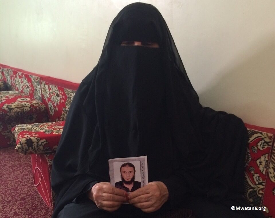 الصورة لـ( آسيا محمد علي ) والدة وضاح الهتاري مع صورة نجلها المجني عليه في منزلها يوم السبت 18 أكتوبر 2014.