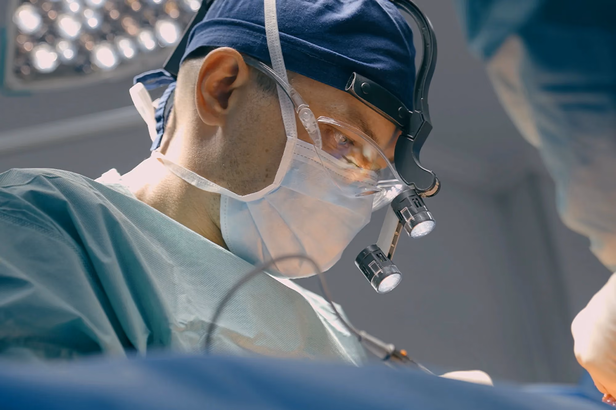 Closeup of a neurosurgeon’s face as he intently performs a procedure in the operating room and provides neurosurgical care in Santa Barbara