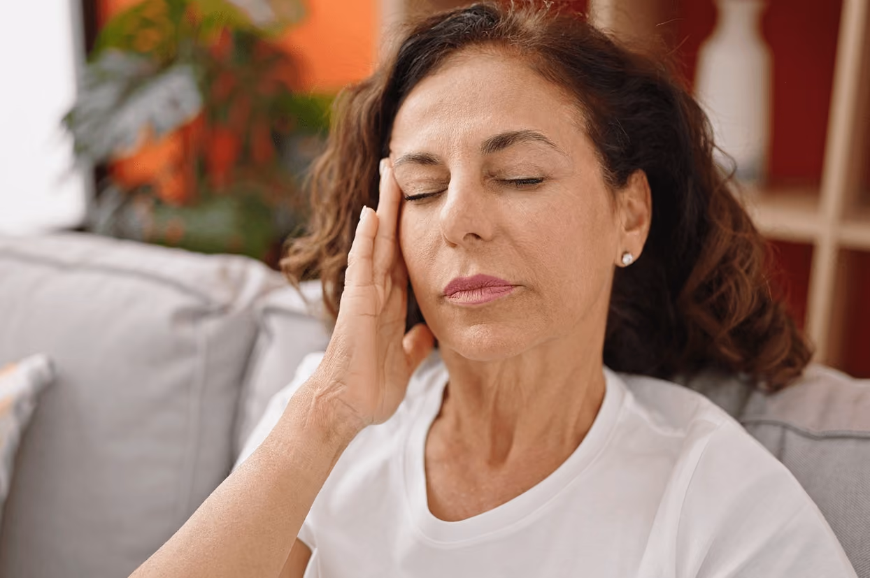 Middle-aged woman touching her face in pain from facial nerve discomfort, seeking treatment from the best doctor for trigeminal neuralgia in Los Angeles.