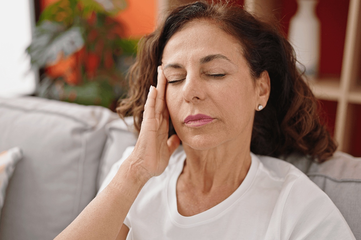 Middle-aged woman touching her face in pain from facial nerve discomfort, seeking treatment from the best doctor for trigeminal neuralgia in Los Angeles.