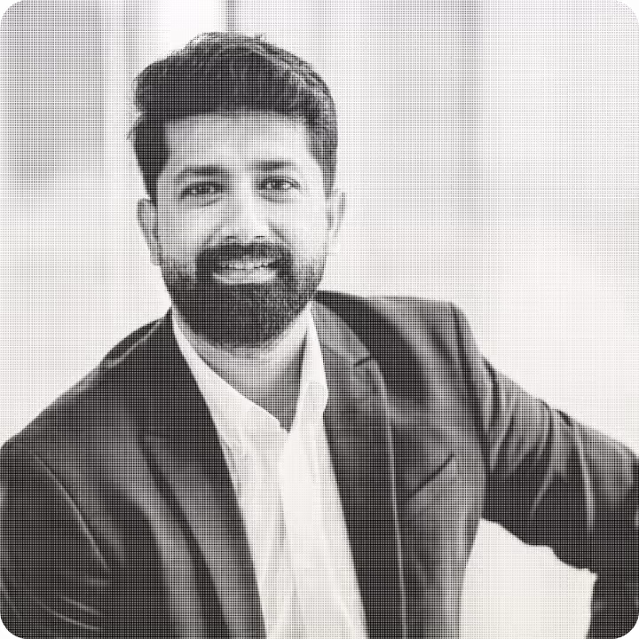 Portrait of a smiling man with a beard wearing a dark blazer and a white shirt.