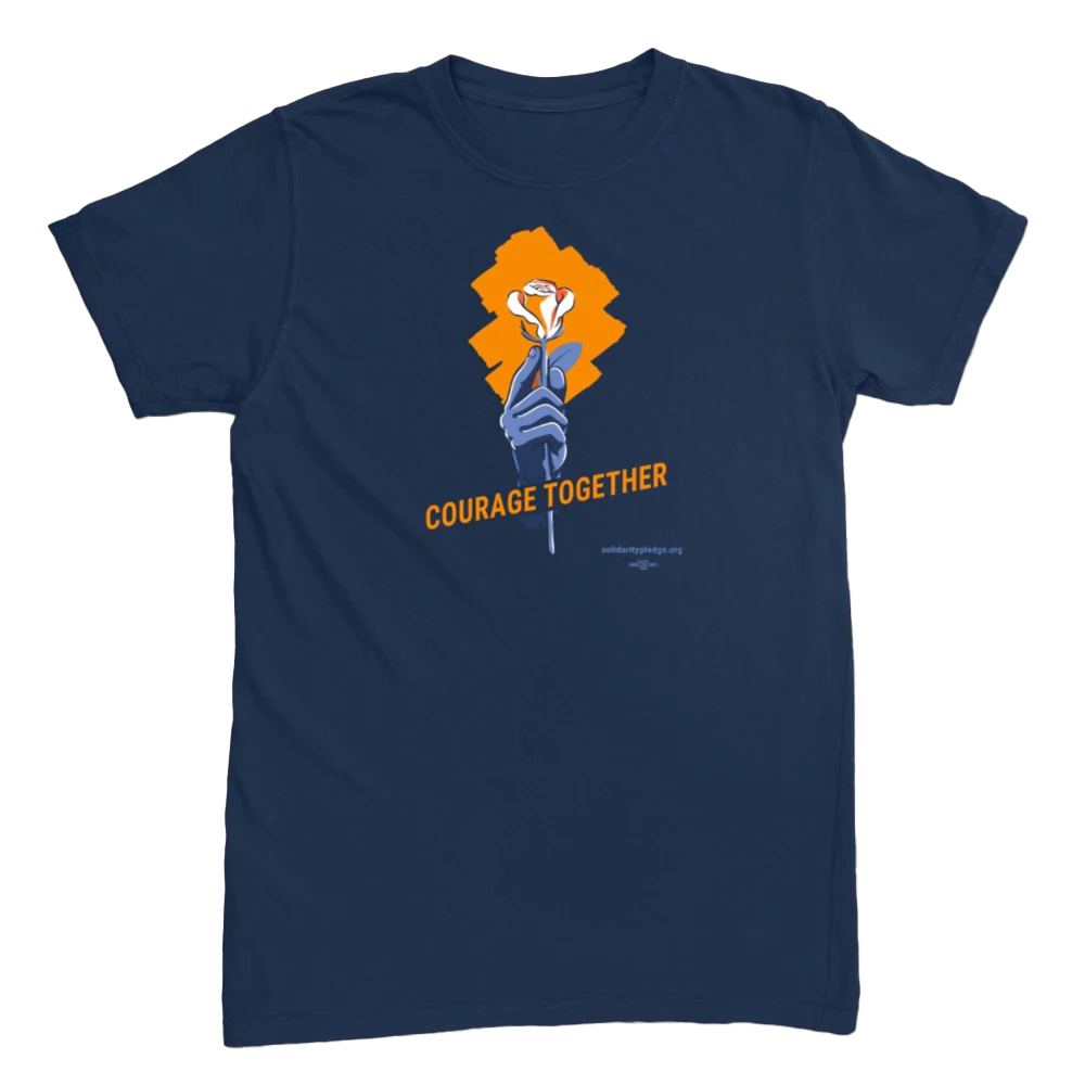 A blue short-sleeved t-shirt with a logo of a hand holding an orange rose and the words "Courage Together"