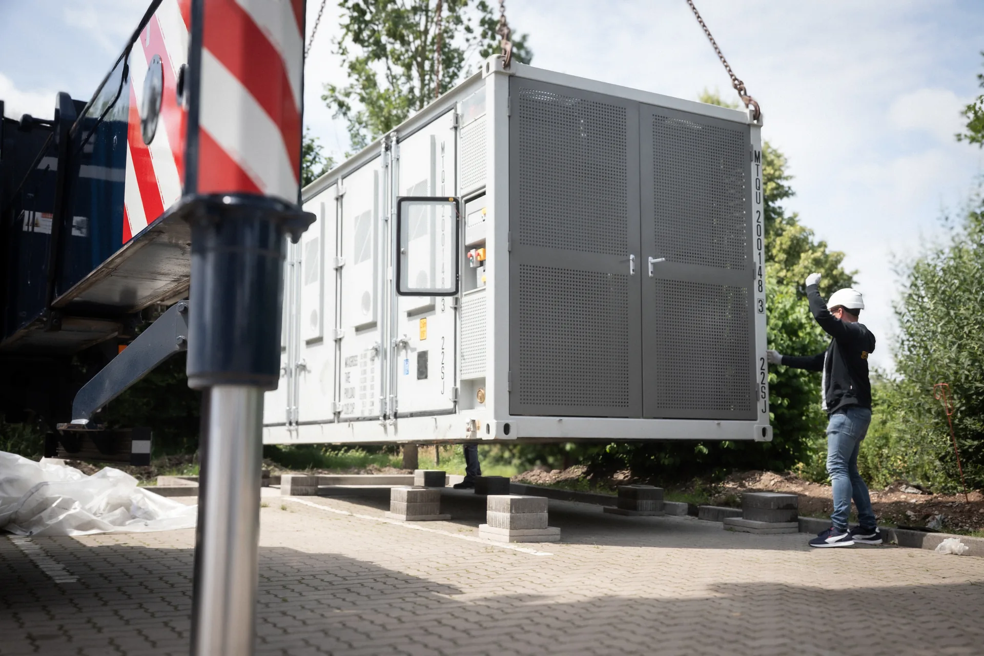 Crane lifting a PHENOGY container battery system at an installation site