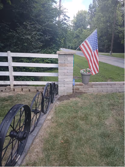 Fence post connected to brick pole with American Flag