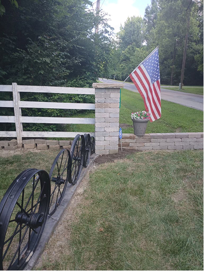 Fence post connected to brick pole with American Flag
