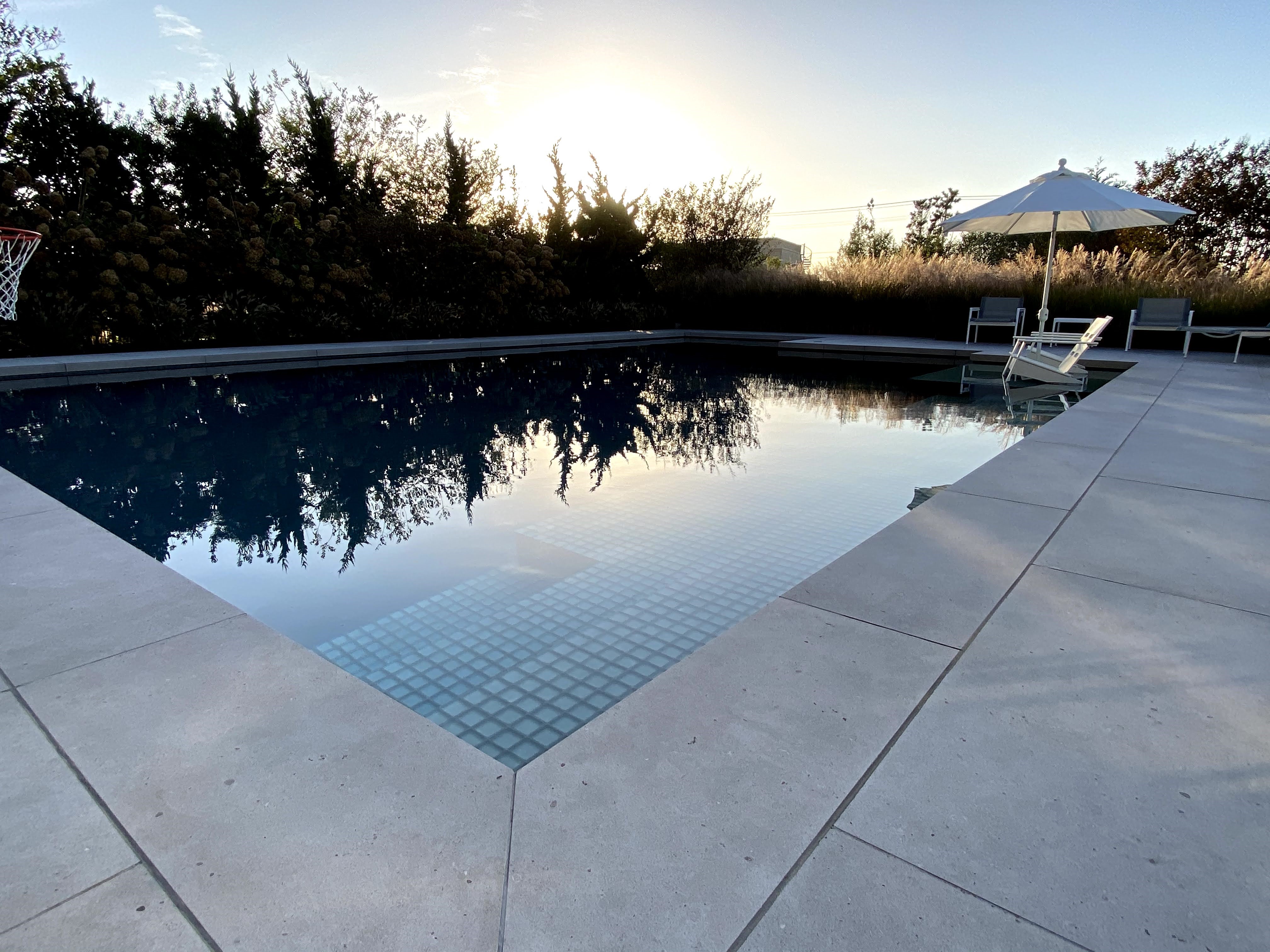 Long view of minimalist pool and timber tones, Loveladies, NJ