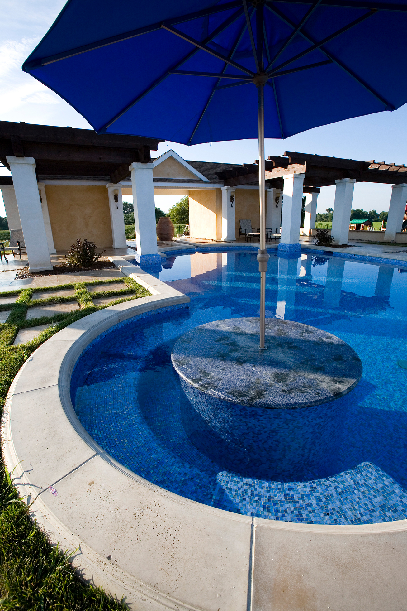Covered pergola walkway looking out to the Mediterranea luxury pool and pavilion in Newtown, Pennsylvania.