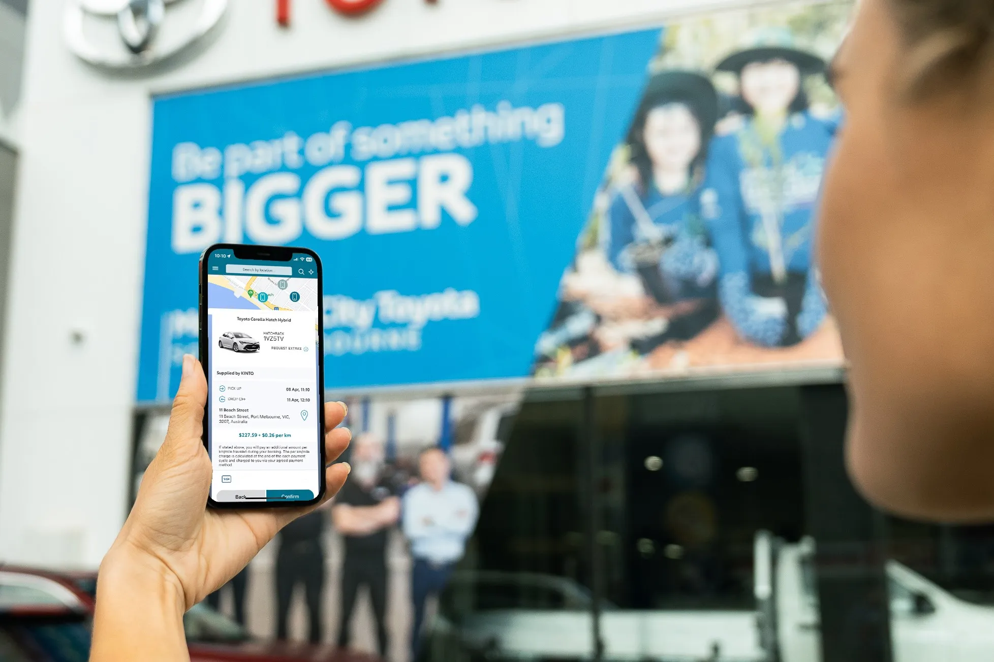 KINTO Camry Dealership woman Holding phone with KINTO car hire app