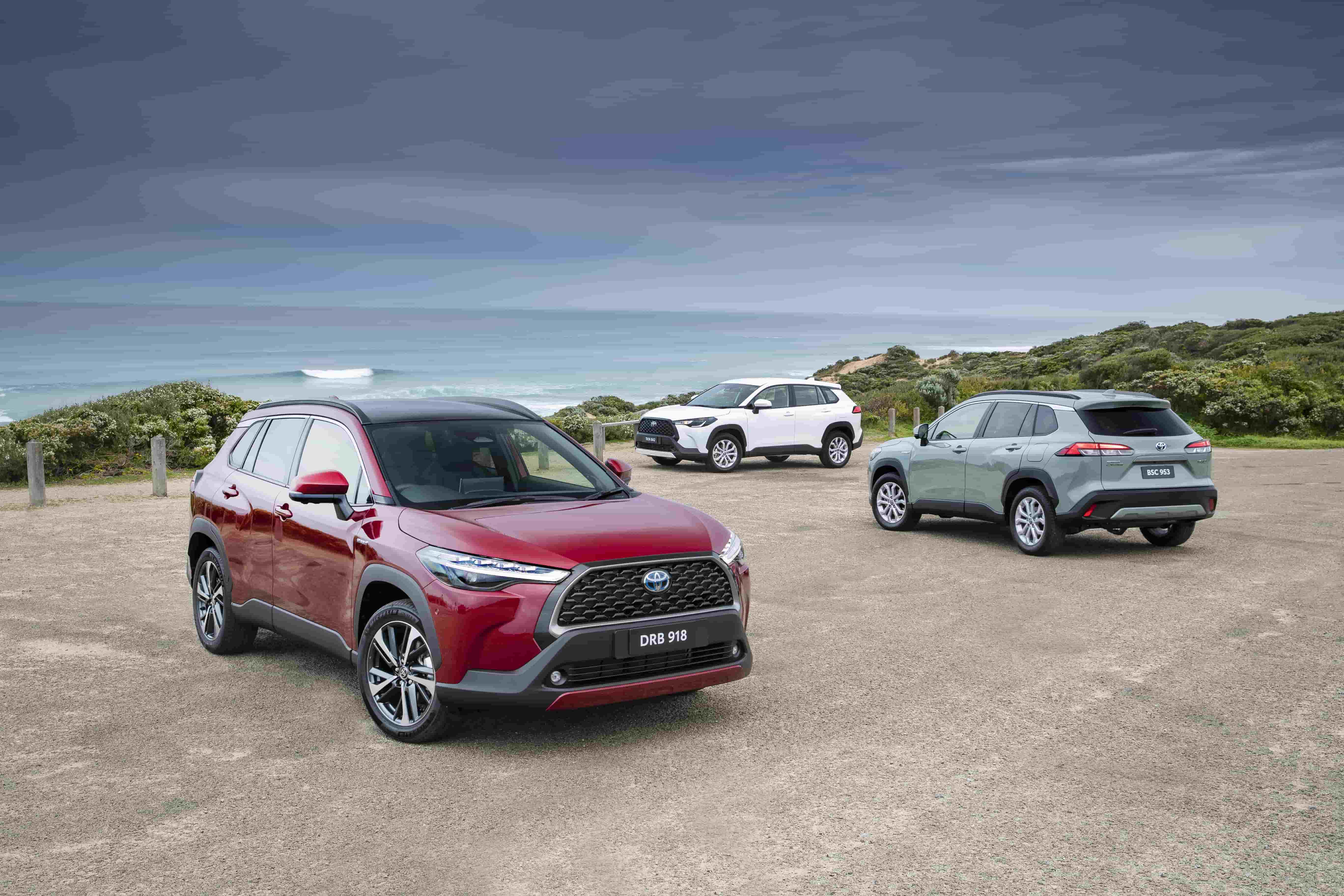 3 Corolla Cross Hybrids parked near each other looking over the ocean.