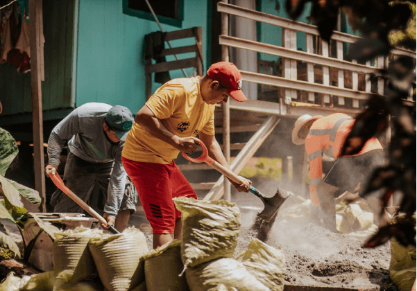 A man shoveling sand into a pile of bags.