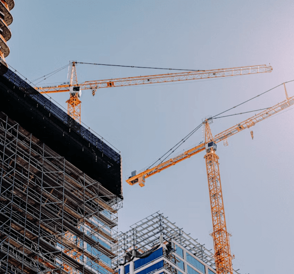 A group of cranes that are next to a building.