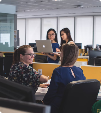 A group of people sitting around a table with laptops.