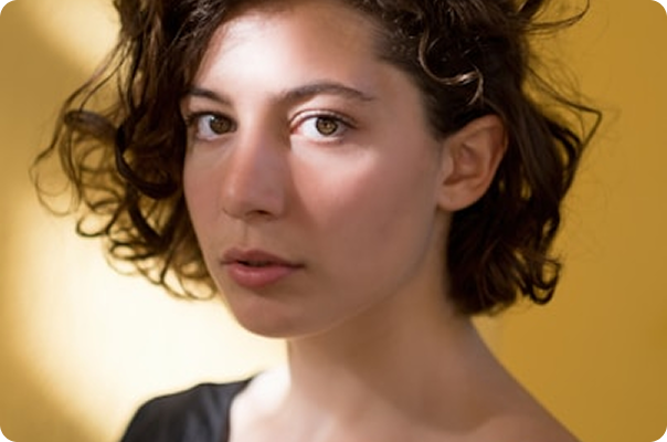 Portrait of a woman with curly hair against a warm golden background