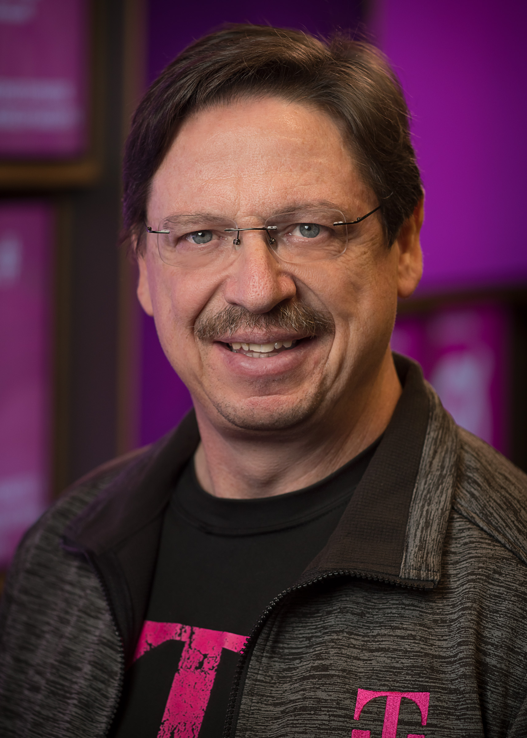 Smiling middle-aged man in glasses and T-Mobile branded jacket