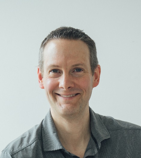 Smiling professional man in gray shirt against neutral background