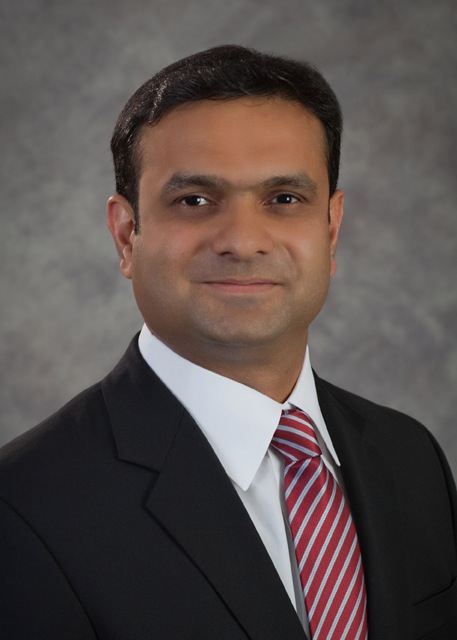 Professional headshot of a smiling businessman in a black suit