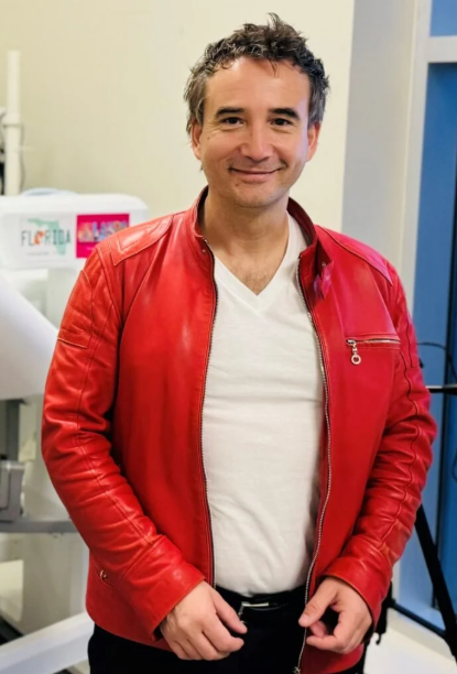 Smiling person in red leather jacket standing in office setting