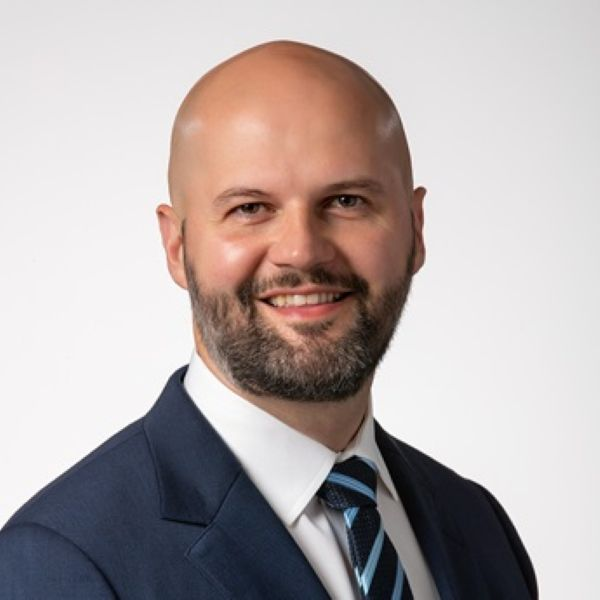 Smiling professional in navy suit and tie with beard and bald head