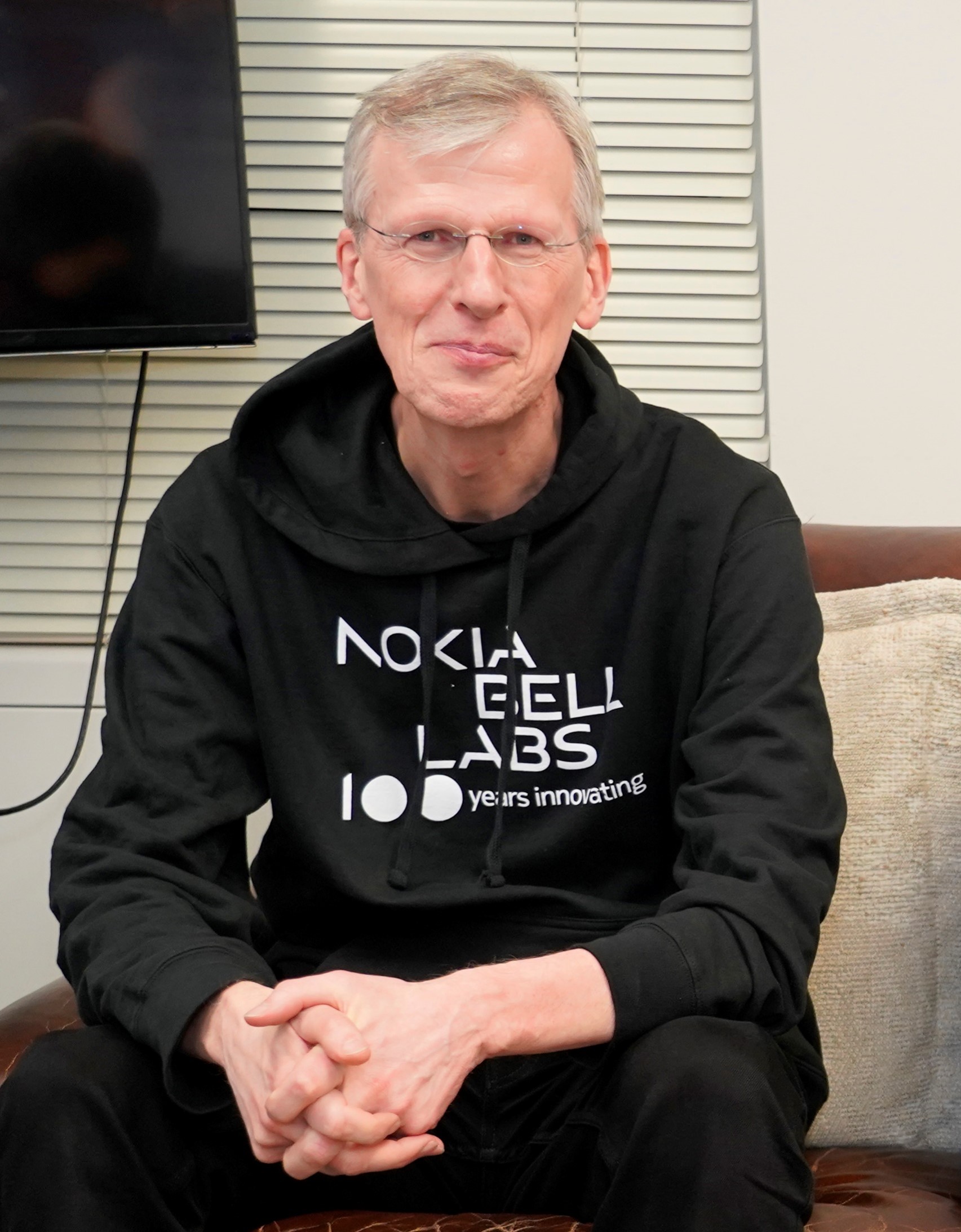 Senior executive in Nokia Bell Labs hoodie sitting and clasping hands