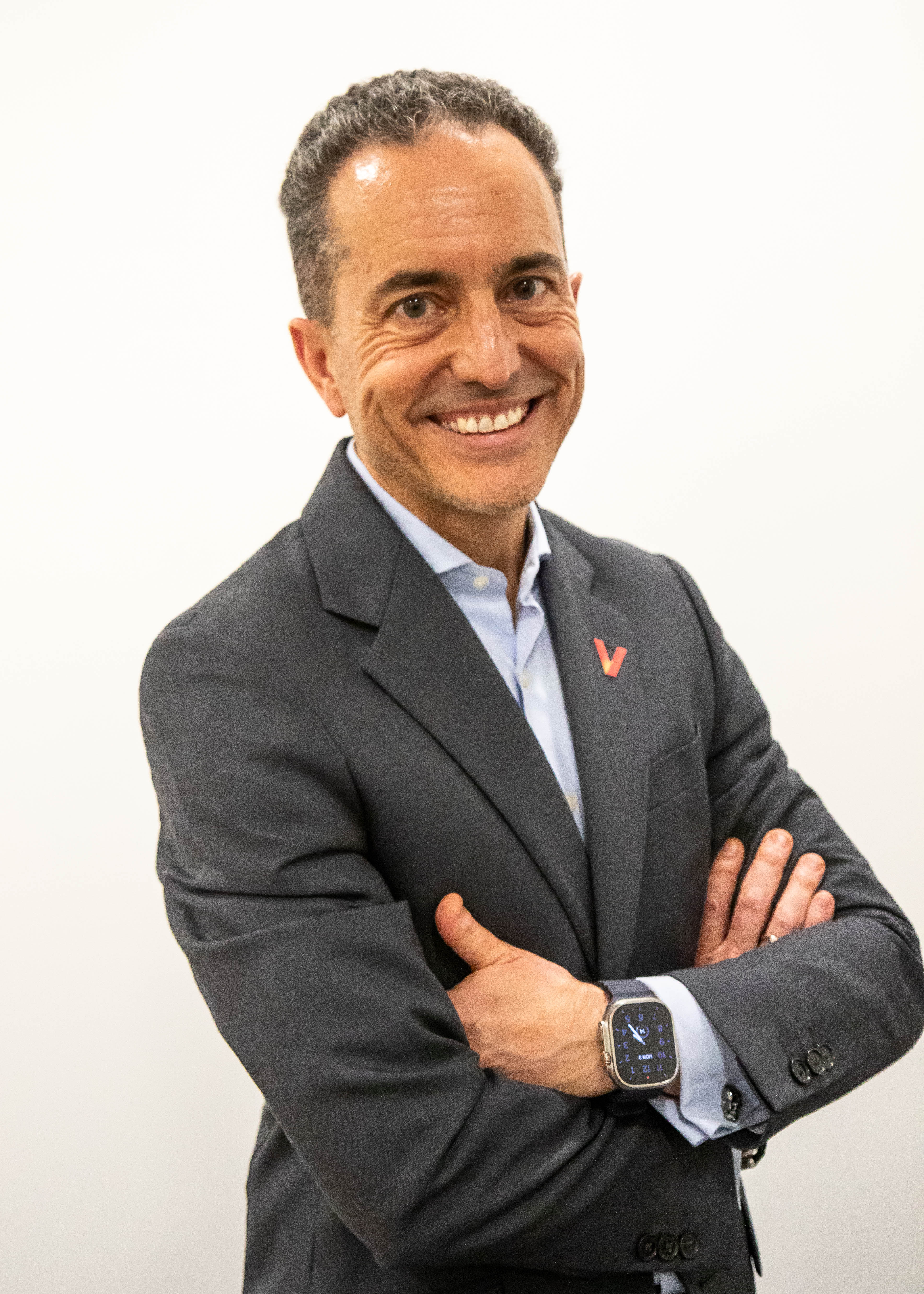 Smiling professional in gray suit with crossed arms and smartwatch