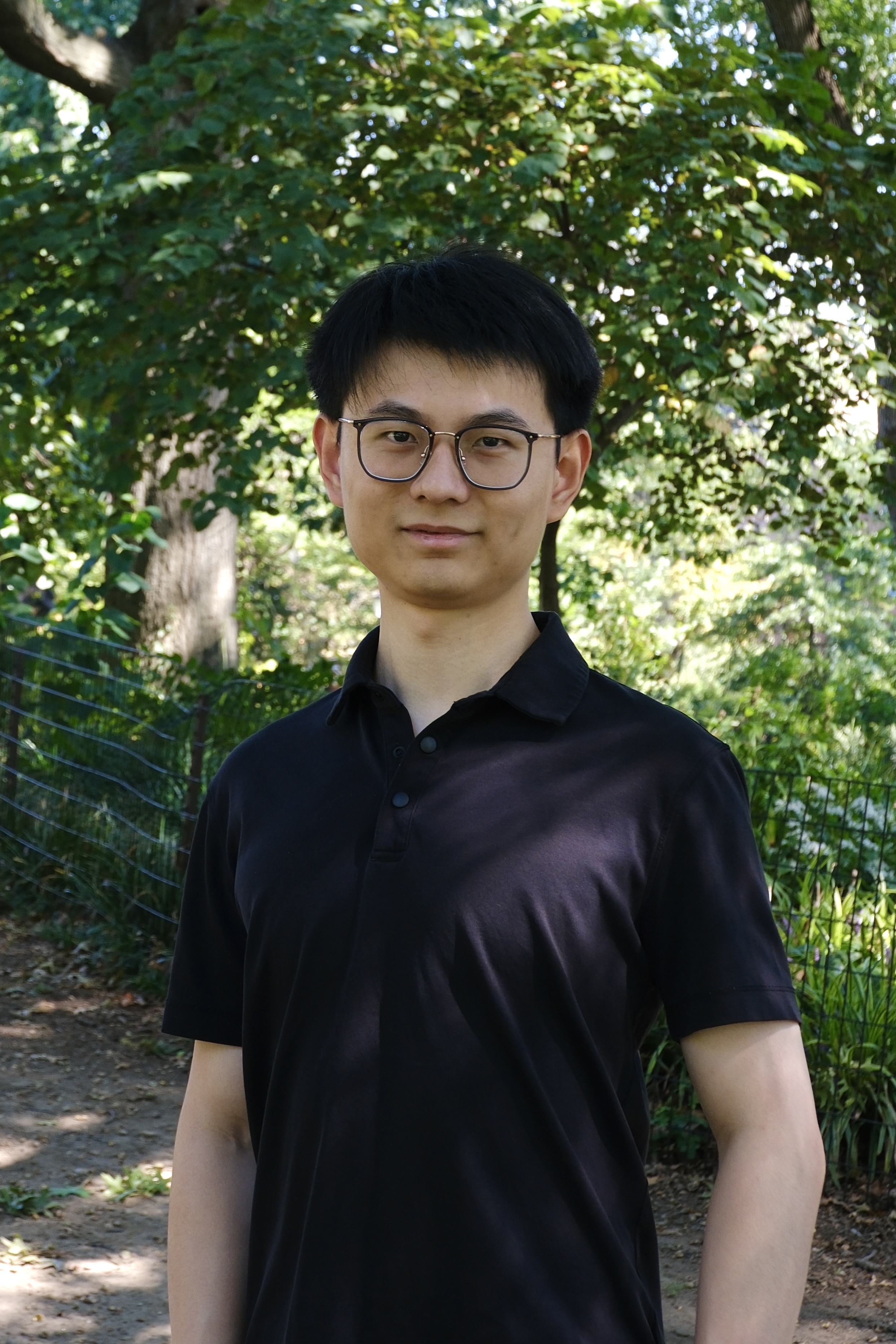 Person in black shirt standing in a lush green forest background
