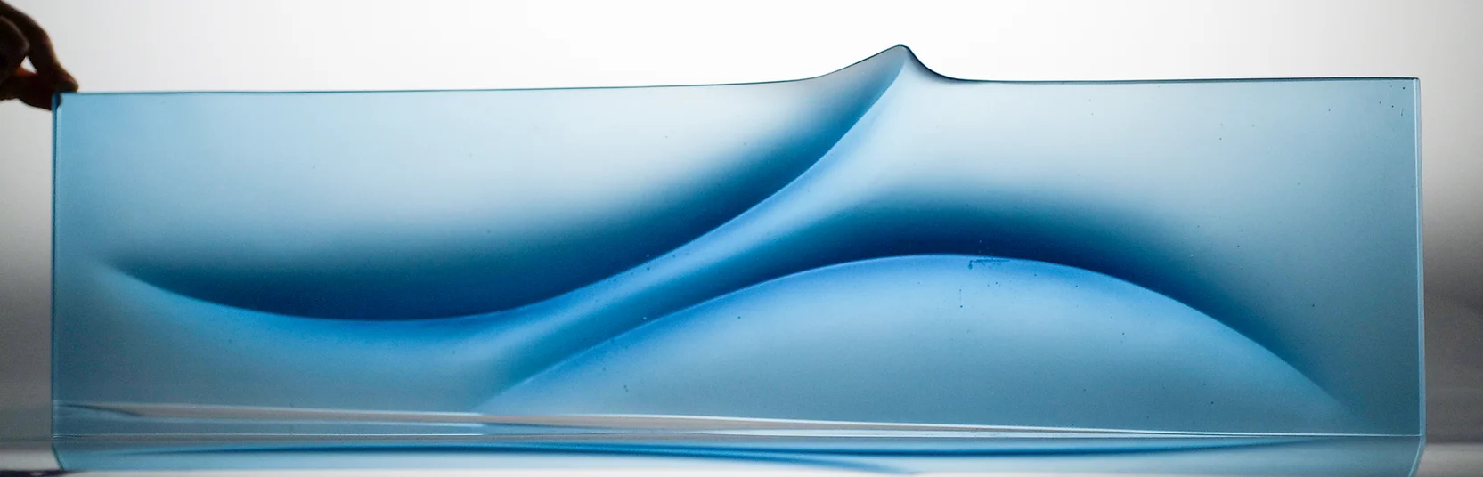 Horizontal blue sculpture in a light gallery space