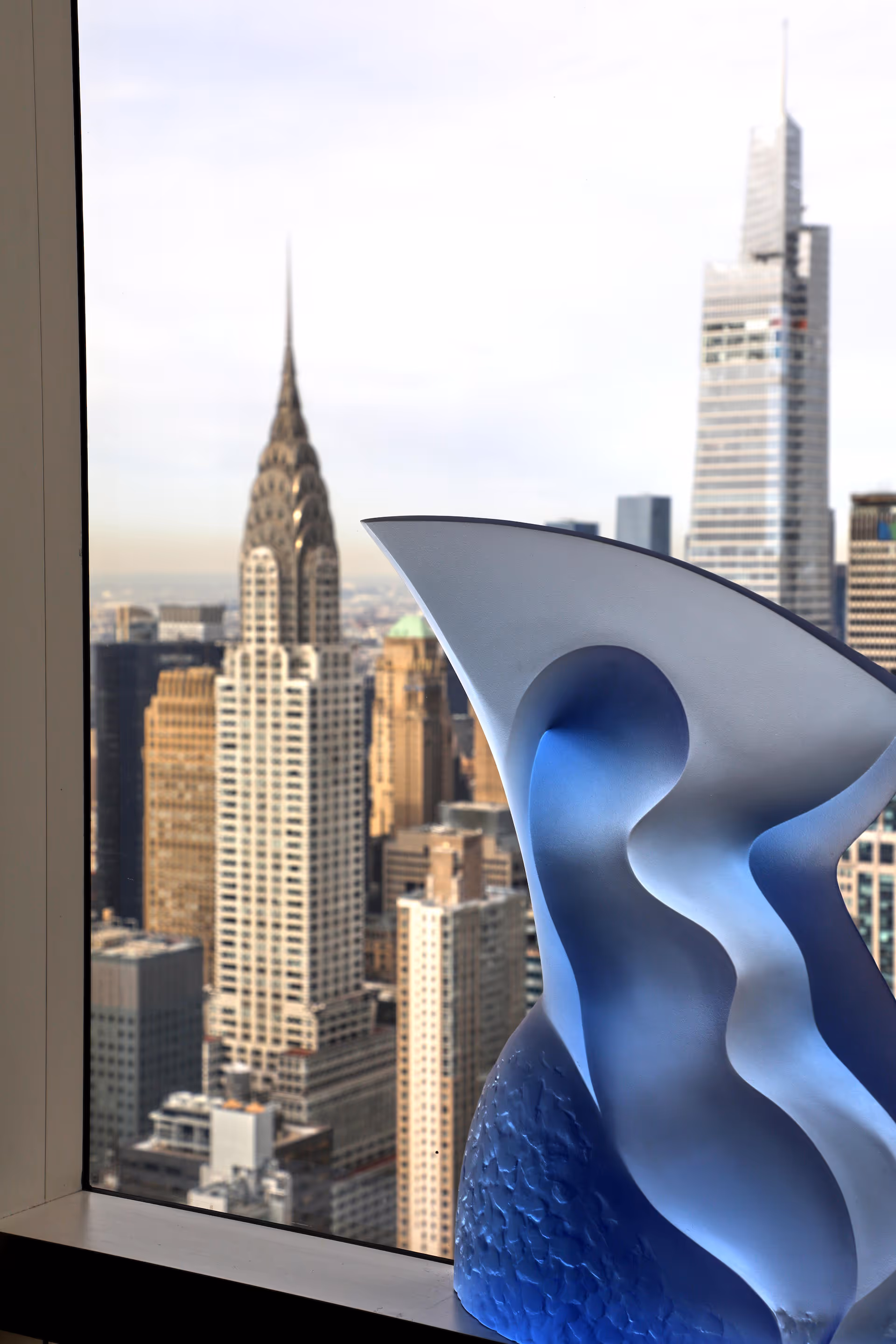 Blue sculpture displayed near a New York skyline
