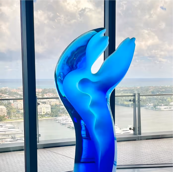 Big blue sculpture staying in a white glass background