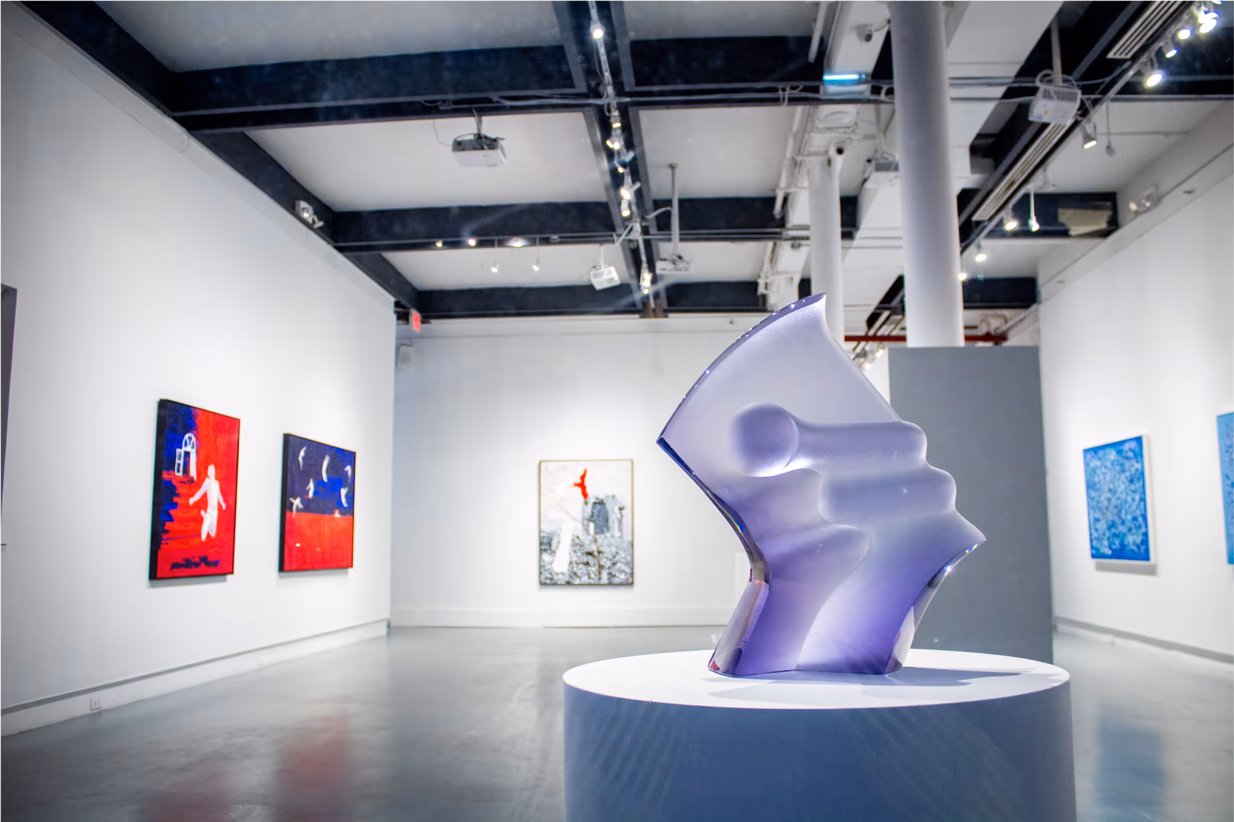 Purple glass sculpture in a gallery with paintings on the walls