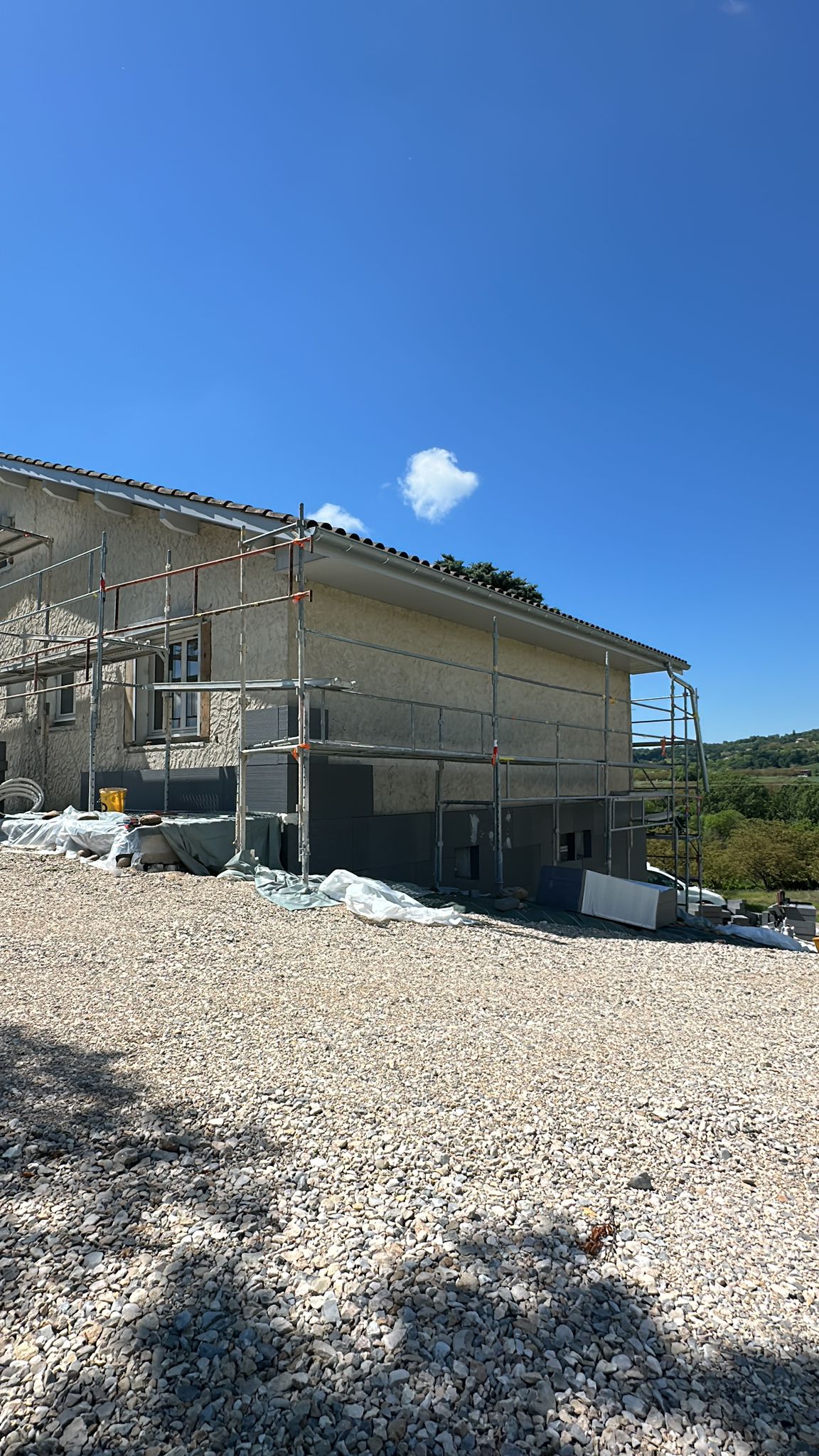 Chantier d'isolation thermique par l'extérieur à Barbières avec échafaudage et panneaux gris par DLS Facade.