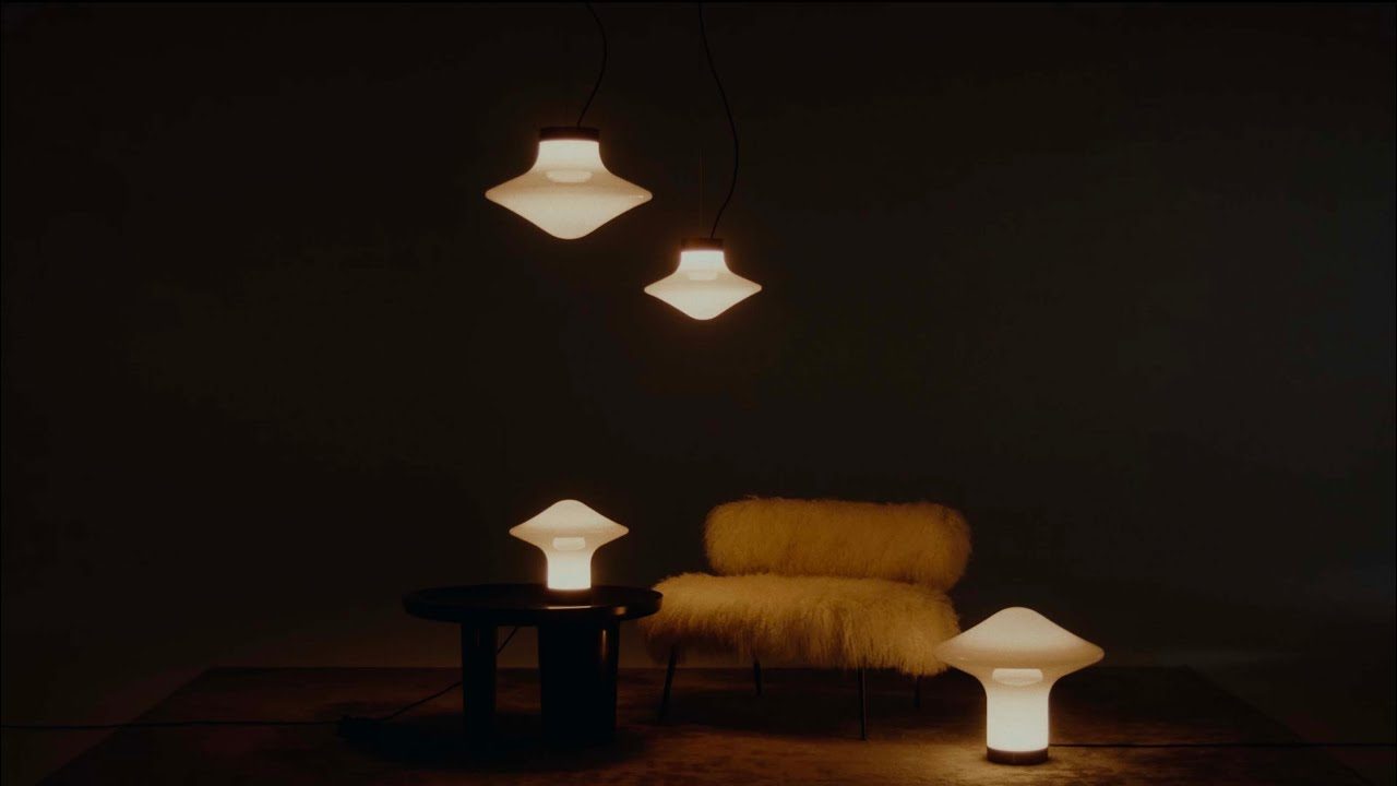 Brokis Trottola pendant and table lights glowing in a dark interior with a sheepskin armchair