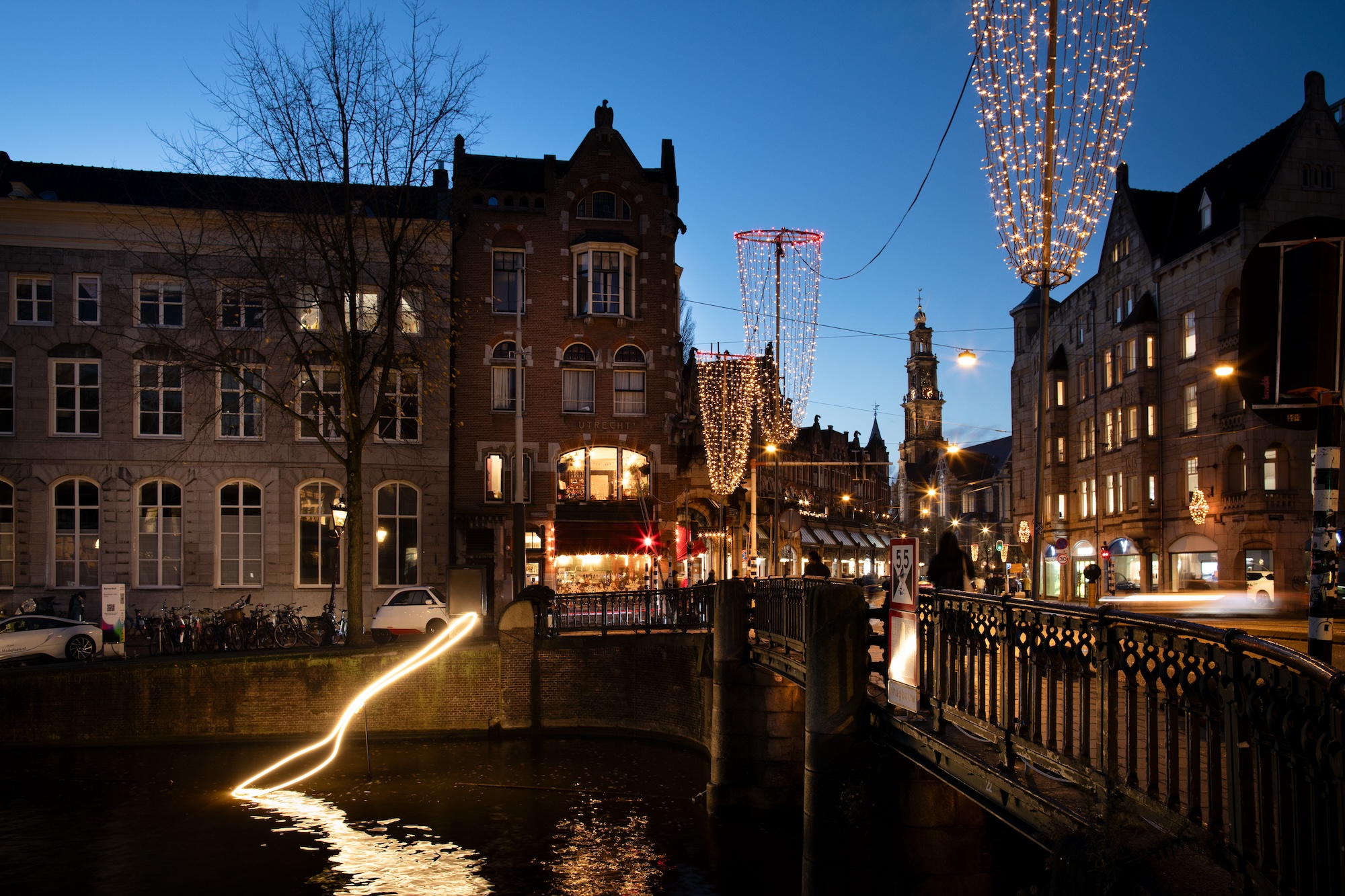 A close up photograph of the spoonful light installation shows the glowing outline of the spoon resting on the canal surface