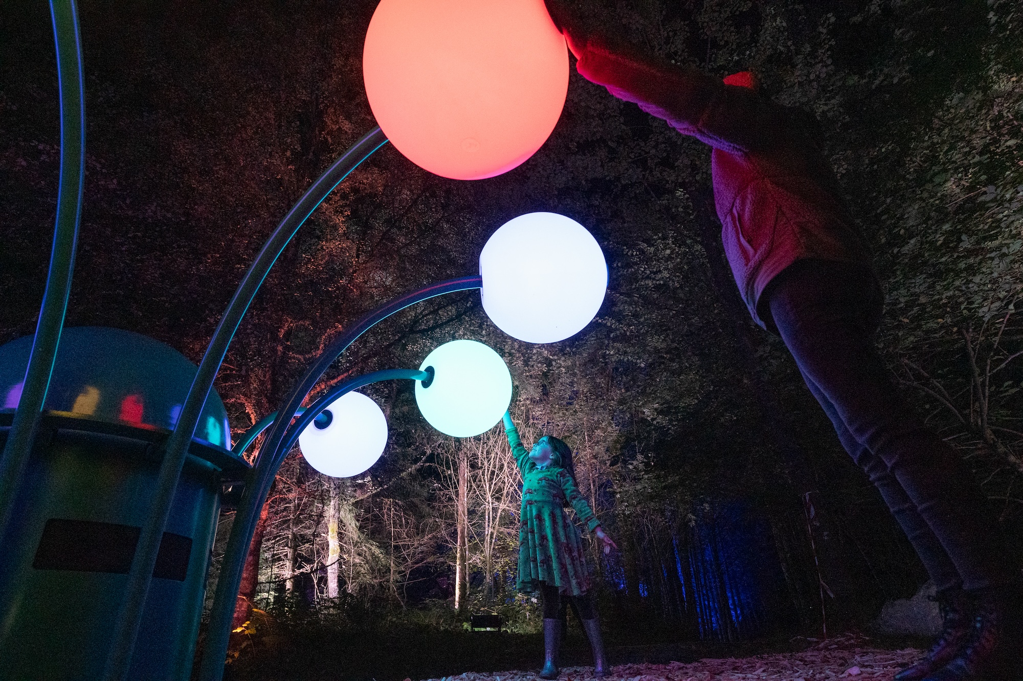 a close up view of a child interacting with a light installation with bulbs that stem outwards like a flower from a central point