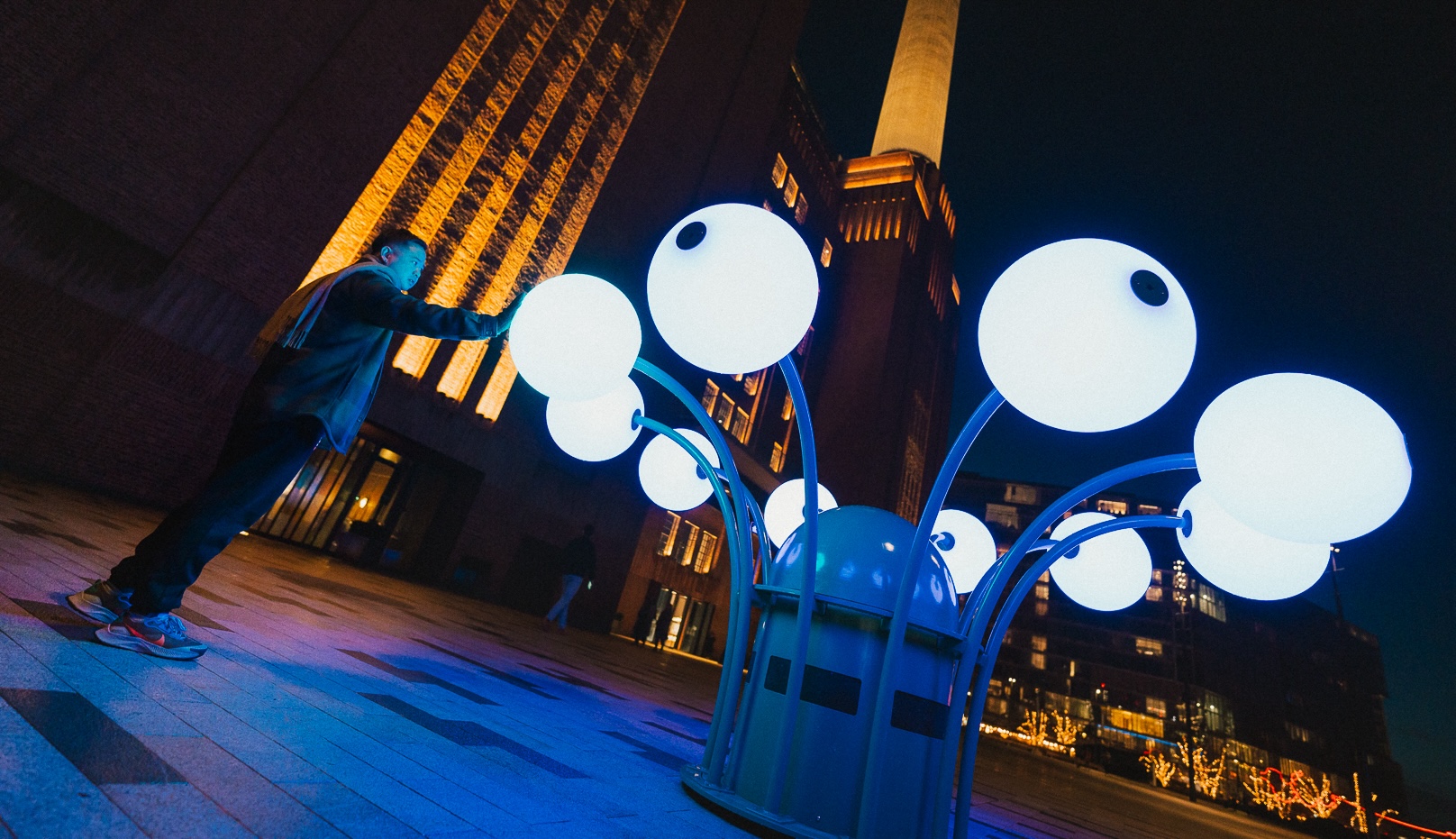 A light installation with bulbs that stem outwards like a flower from a central point, situated in front of battersea power station