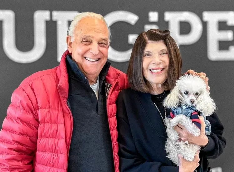 Happy pet owners with their dog at SurgiPet lobby after successful veterinary surgery.