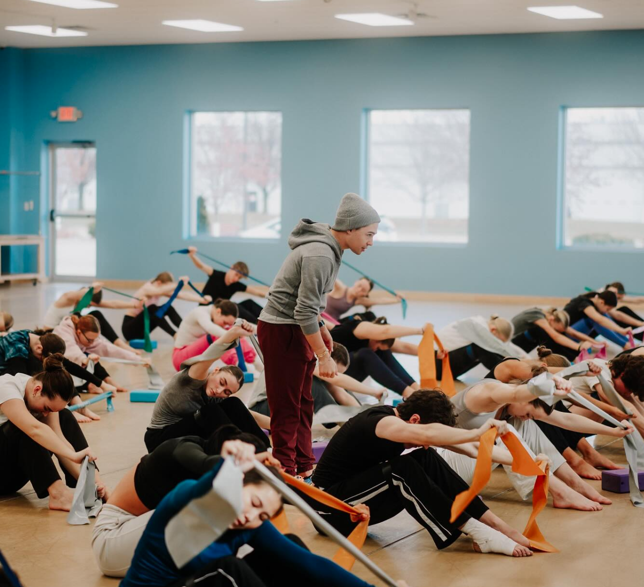 Instructor leading a large group stretch class using resistance bands.