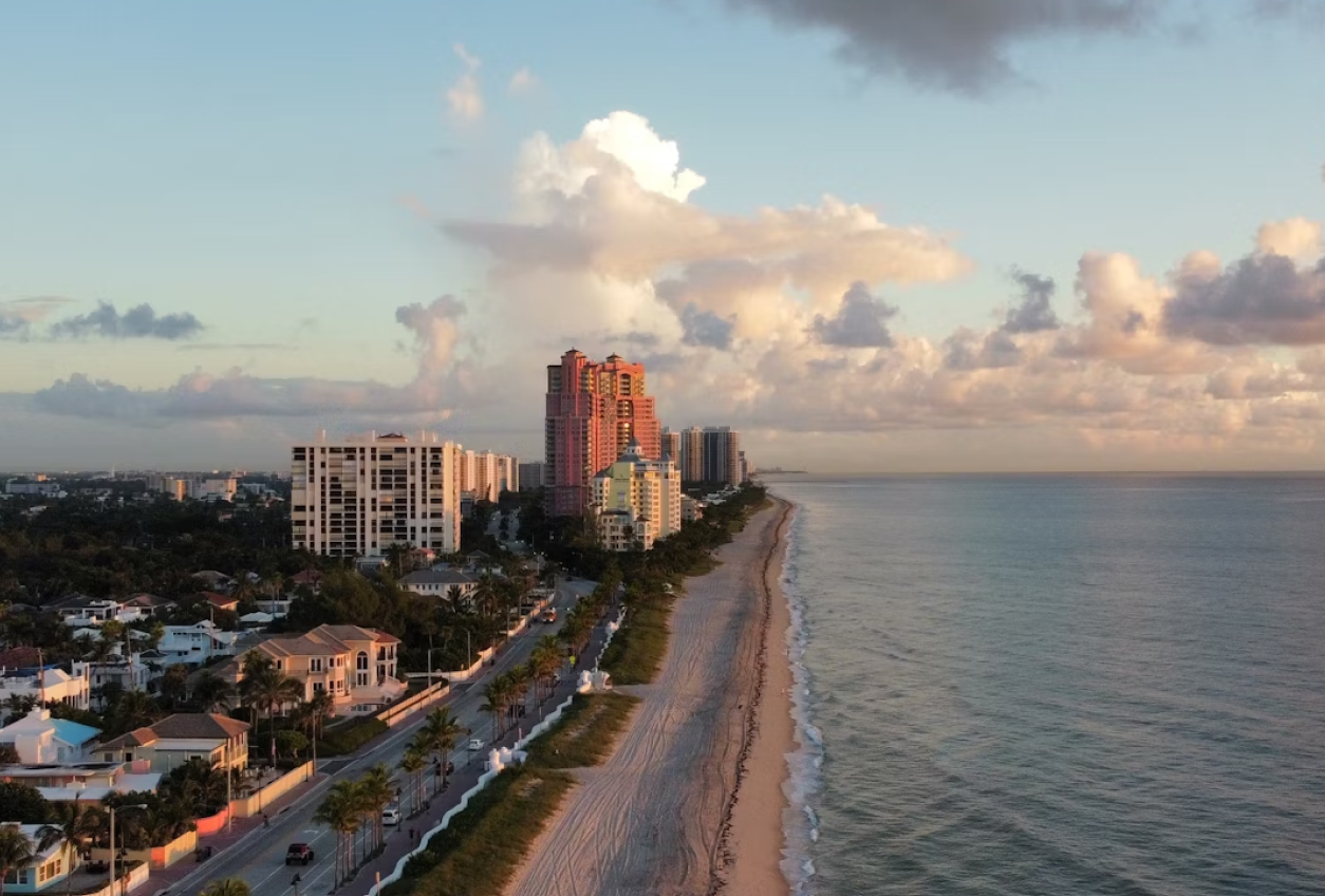 Aerial view of a coastal city with beachfront high-rises at sunset.
