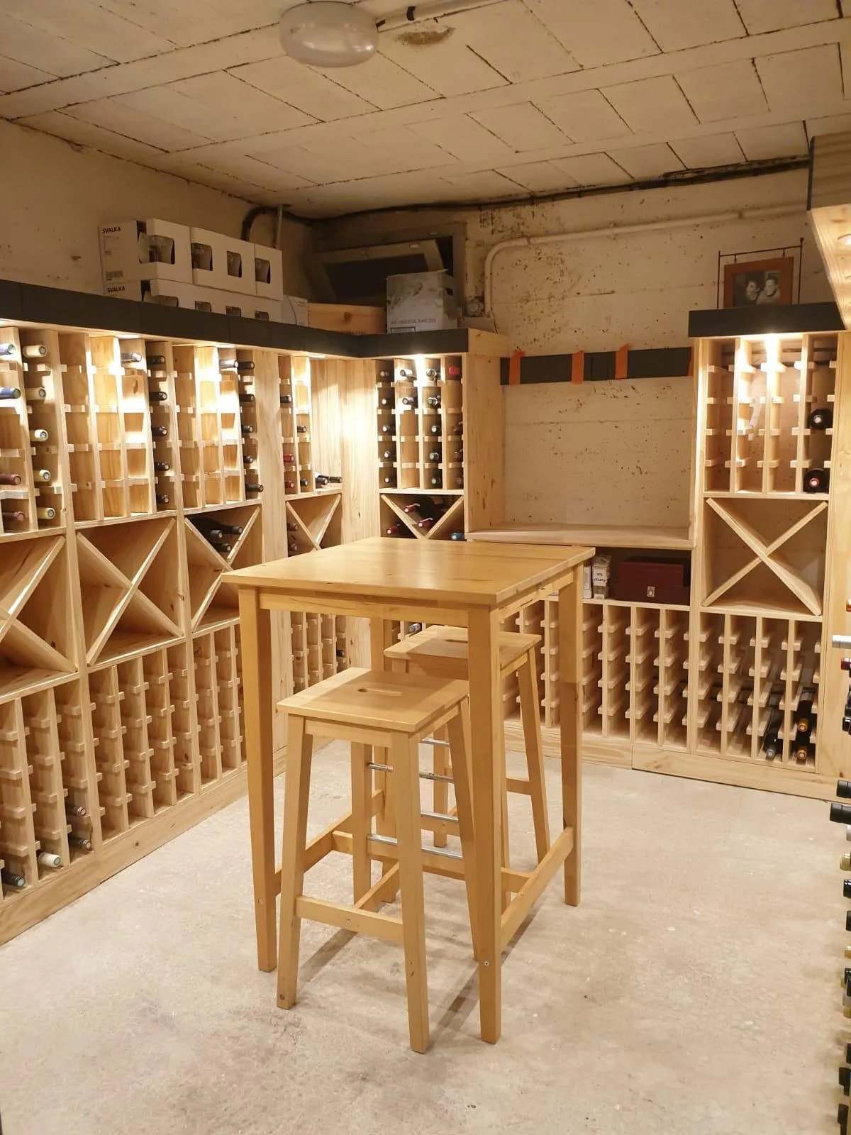 Cave à vin en bois avec table haute et tabourets.