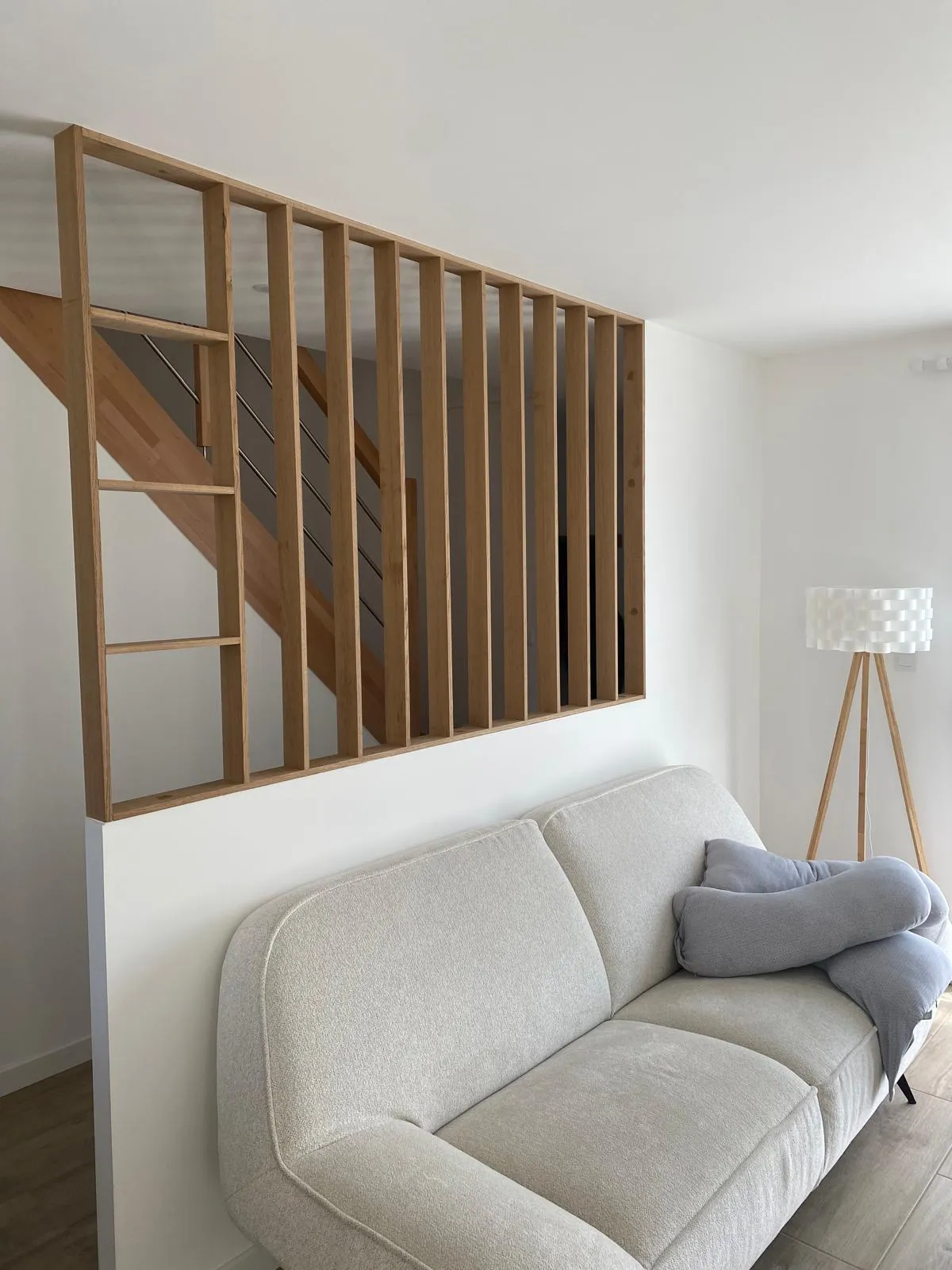 Claustra en bois derrière un canapé clair.