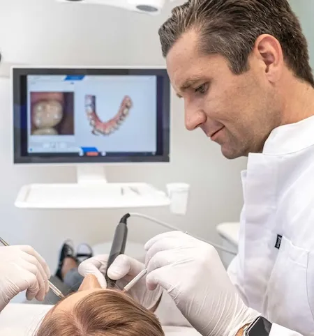 Zahnarzt verwendet digitales Intraoralscanner-Gerät zur Untersuchung der Zähne eines Patienten im Behandlungsstuhl.