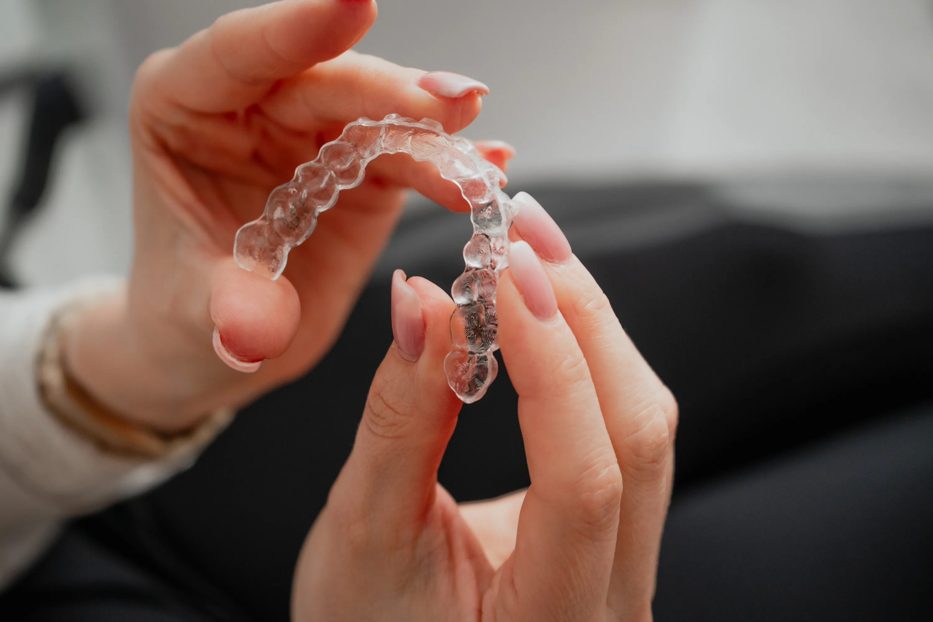 Hand hält eine transparente und loose Zahnspange für Erwachsene.