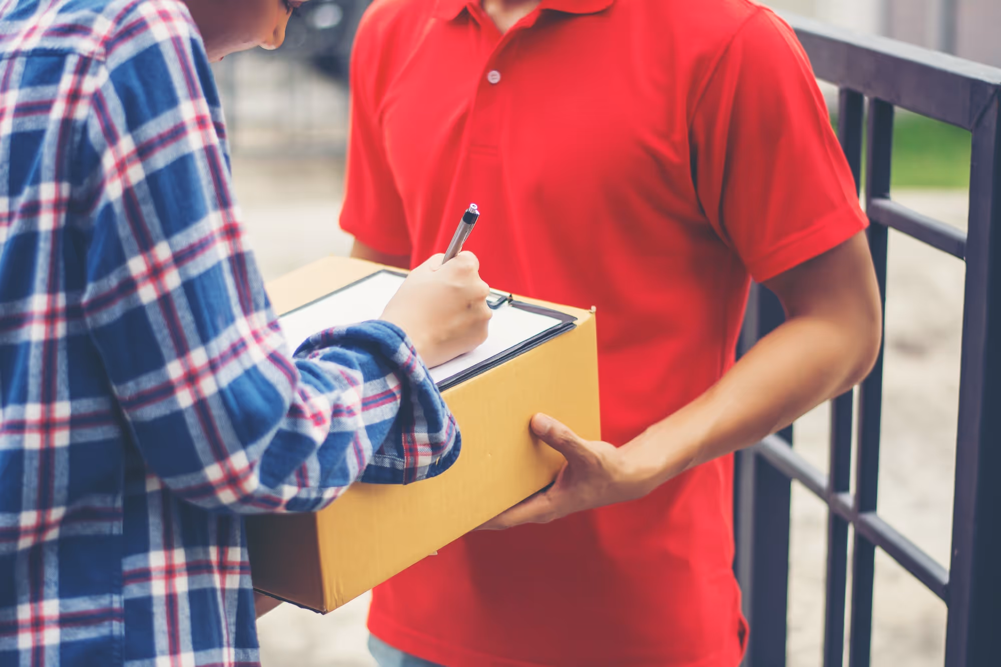 Man signing a form while receiving a package from a delivery person