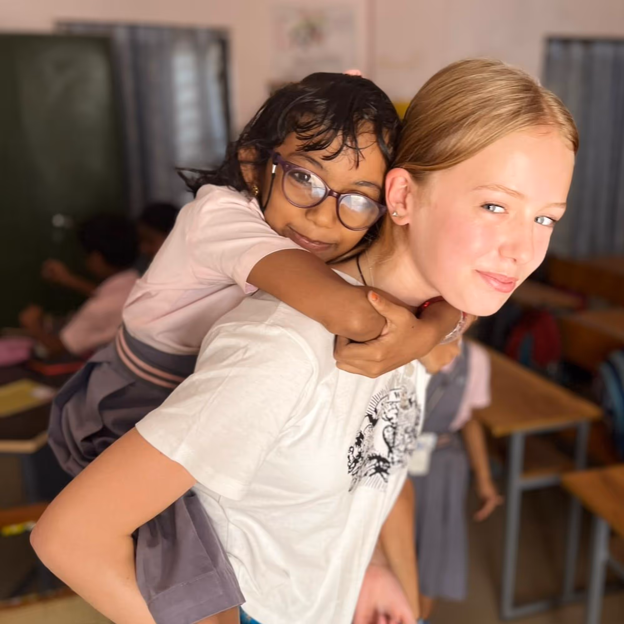gap year to India volunteering in school with girl on back of gap year student smiling
