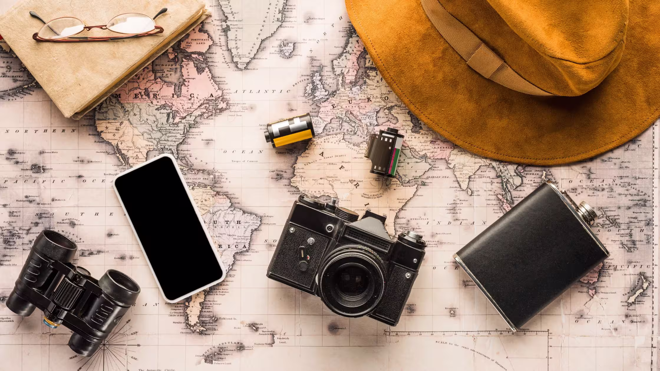 how to set a budget for your gap year map with camera, phone, hat and binoculars